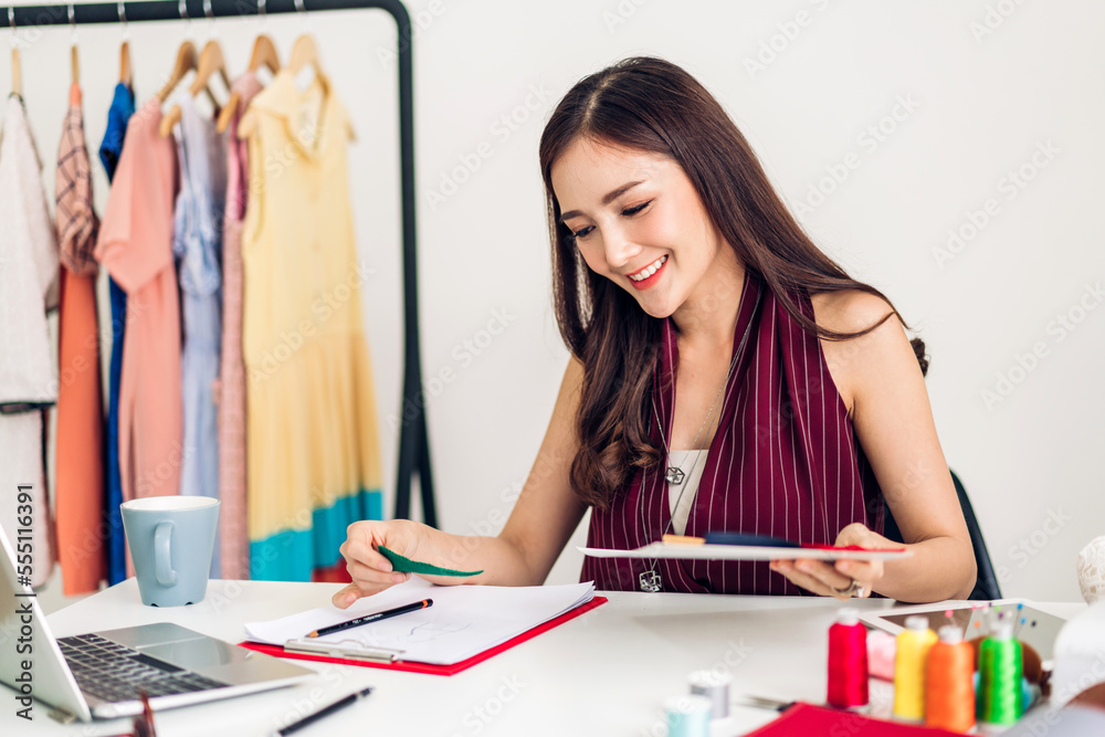 Portrait of young beautiful asian woman fashion designer stylish sitting and working with color samples.Attractive young asian girl working with colorful fabrics at fashion studio
