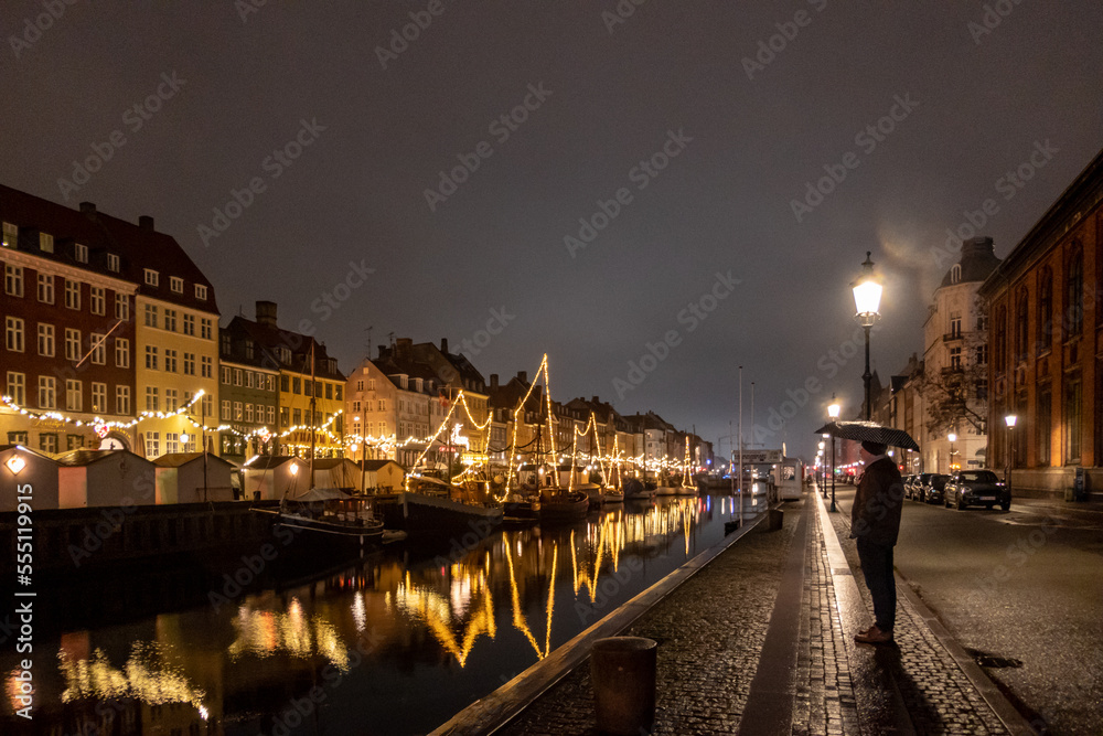 Copenhagen, Denmark  A single male tourist stands at the Nyhavn district at night.