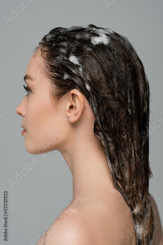 profile of young woman with foamy and wet hair isolated on grey
