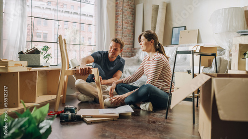 Fotografie Family Moving in and Home Renovations: Happy Couple Assembles Furniture Together, Girlfriend Reads Instructions and Boyfriend Follows them with some Force