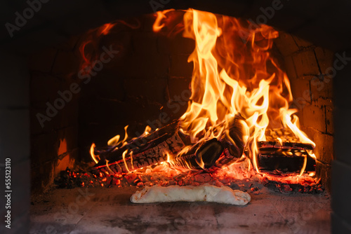Italian food. Traditional calzone preparing in oven with open fire