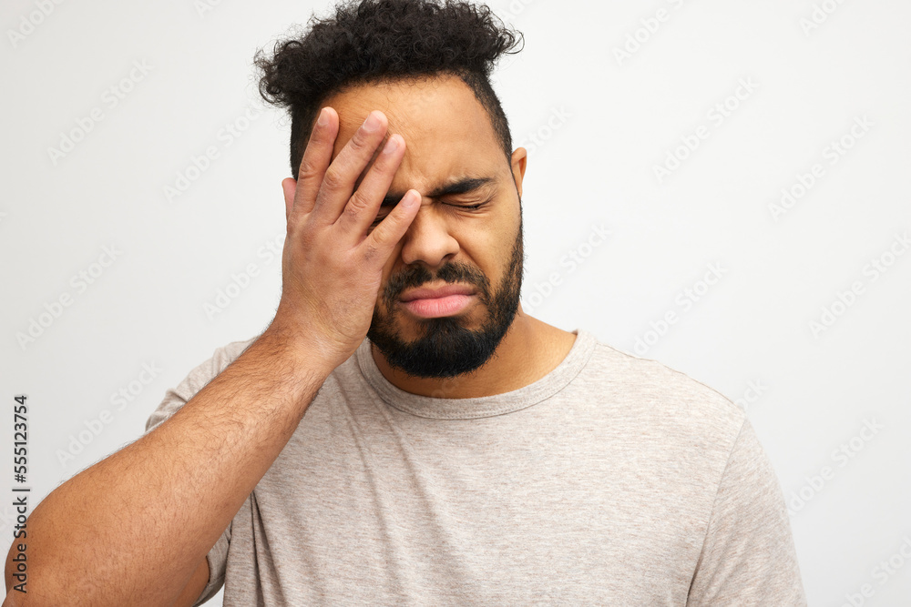 Portrait of stressed Jamaican man with headache or regretting something, isolated on white background, looking down suffering from headache after hard working day Portrait of stressed Jamaican man with headache or regretting something, isolated on white background, looking down suffering from headache after hard working day