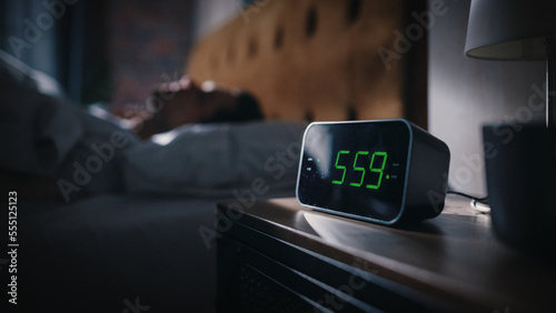 Handsome Man Wakes Up and Turns off Alarm Clock. Proceeds to Have a Productive Day of Work. Stylish Apartment. Focus on the Clock Showing Five Hours and Fifty Nine Minutes in the Morning