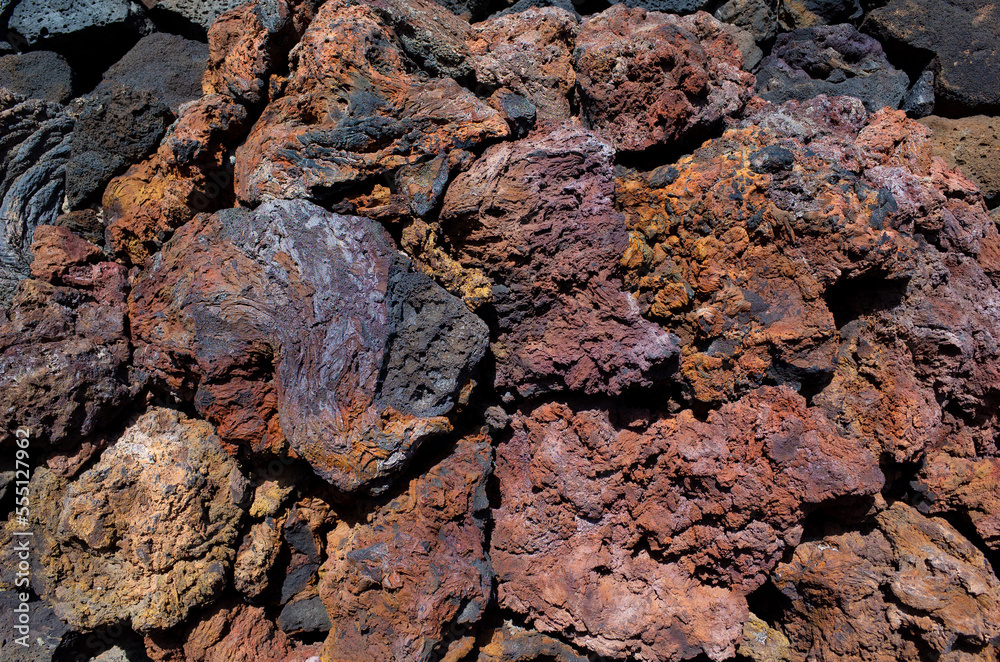 View of volcanic rocks from past volcano eruption on Lanzarote island. Beautiful red brownish and black rough texture stones made by lava. Close up view of basaltic lava rocks. Canary Islands, Spain. View of volcanic rocks from past volcano eruption on Lanzarote island. Beautiful red brownish and black rough texture stones made by lava. Close up view of basaltic lava rocks. Canary Islands, Spain.