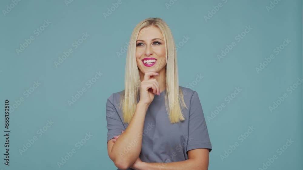 Young beautiful blond girl in the studio. Portrait of emotional girl on blue background.
