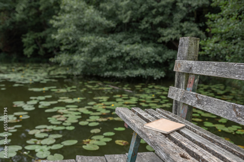 Copybook placed on old wooden bench near pond photo