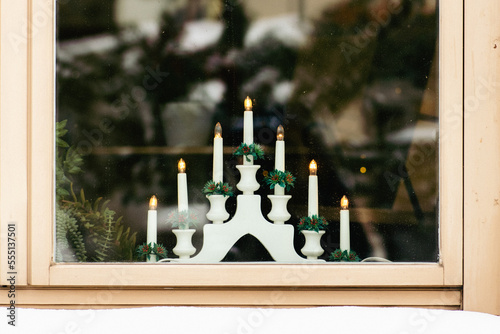 Traditional Swedish Christmas white candlestick bridge with lights by a wooden window with snow on the windowsill photo