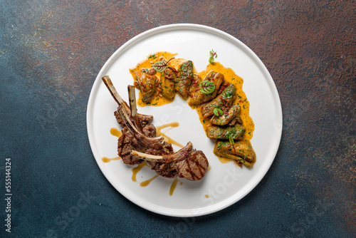 Rack of lamb with auberdine with sauce on white plate top view