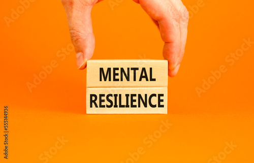 Mental resilience symbol. Concept word Mental resilience typed on wooden blocks. Beautiful orange table orange background. Doctor hand. Business psychological and mental resilience concept. Copy space