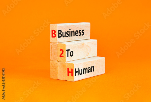 B2H business to human symbol. Concept words B2H business to human on wooden blocks on a beautiful orange table orange background. Business and B2H business to human concept. Copy space. photo