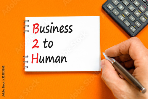 B2H business to human symbol. Concept words B2H business to human on white note on a beautiful orange table orange background. Businessman hand. Business and B2H business to human concept. Copy space. photo