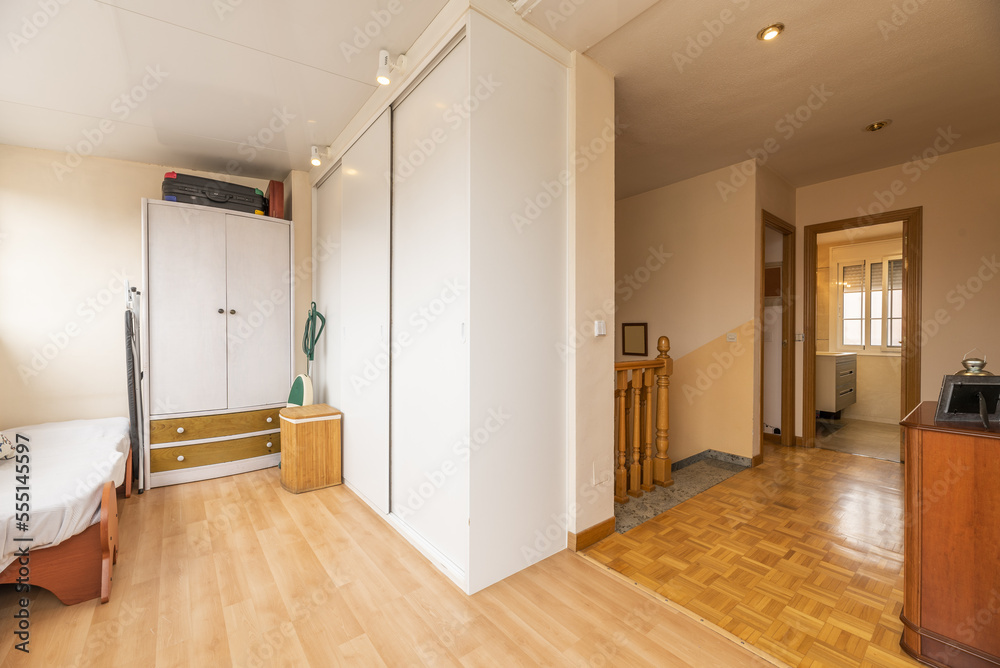 Fototapeta premium An open space with built-in wardrobes, a small bed and access to stairs in a multi-storey detached house