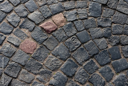 Black cobblestone street pavement with red bocks, top view