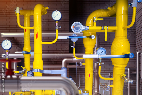 Yellow pipes in basement. Gas industry. Pipes with pressure meters. Gas pipeline near brick wall. Boiler room with gas equipment. Pipes for supply propane. Methane supply for factory. 