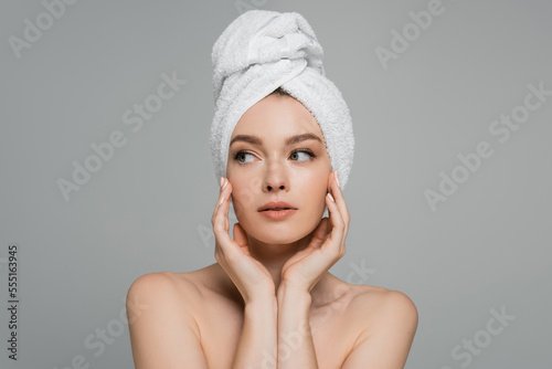 young woman with bare shoulders and towel on head looking away isolated on grey