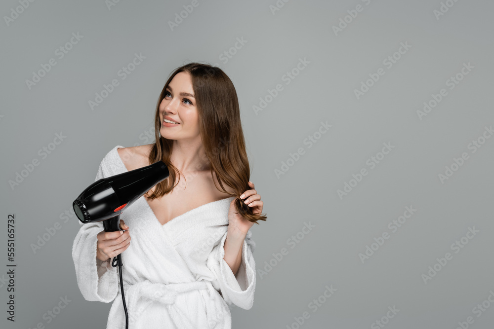 cheerful young woman with shiny hair using hair dryer isolated on grey cheerful young woman with shiny hair using hair dryer isolated on grey