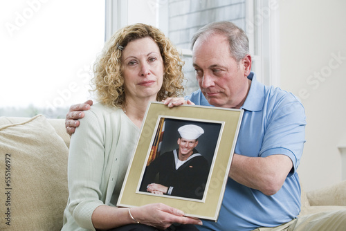 Portrait of a mature couple holding picture of their son working in the military