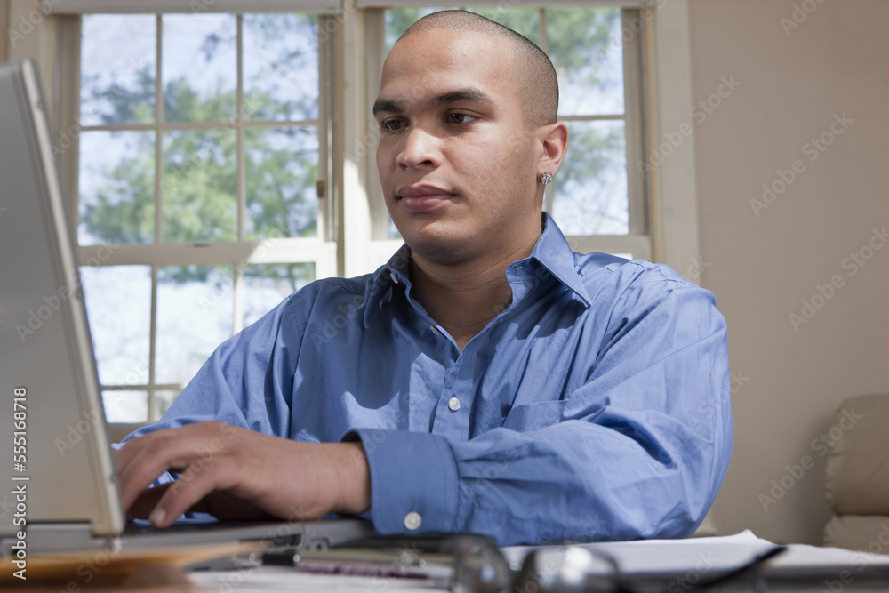 Young male professional working at a table from home with his laptop computer Young male professional working at a table from home with his laptop computer