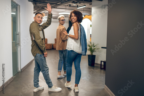 Joyous office employees smiling at somebody in the hallway