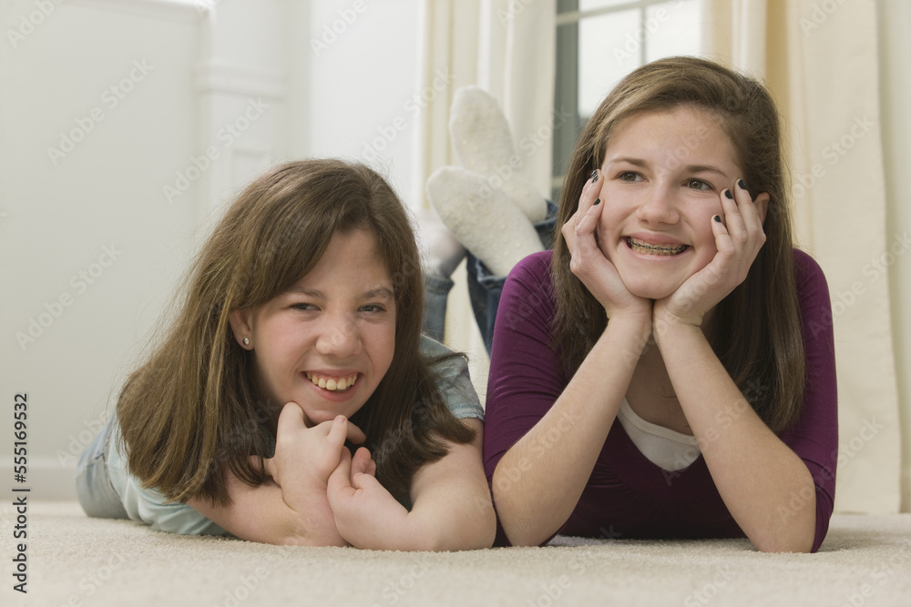 Two teenage girls lying together and smiling, Teenage girl with birth defect talking on a mobile phone Two teenage girls lying together and smiling, Teenage girl with birth defect talking on a mobile phone