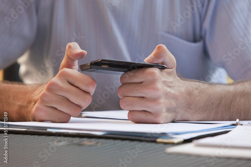 Businessman with Friedreich's Ataxia text messaging on a mobile phone with hand degeneration photo