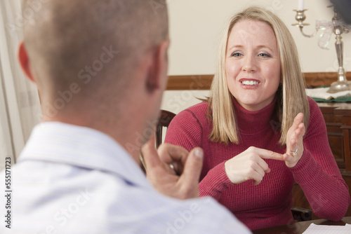 Woman signing the word 'Afford' in American Sign Language while communicating with a man