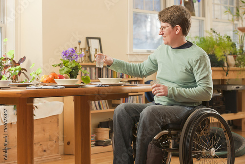 Woman with multiple sclerosis in a wheelchair setting table for dinner photo