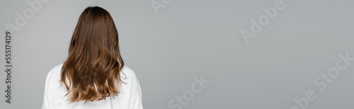 back view of young woman with shiny and healthy hair isolated on grey, banner