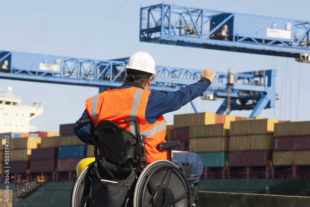 Transportation engineer in a wheelchair giving directions to shipping containers at shipping port