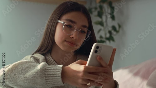 Close up of caucasian teenage girl browsing phone in her bedroom. Shot with RED helium camera in 8K.   