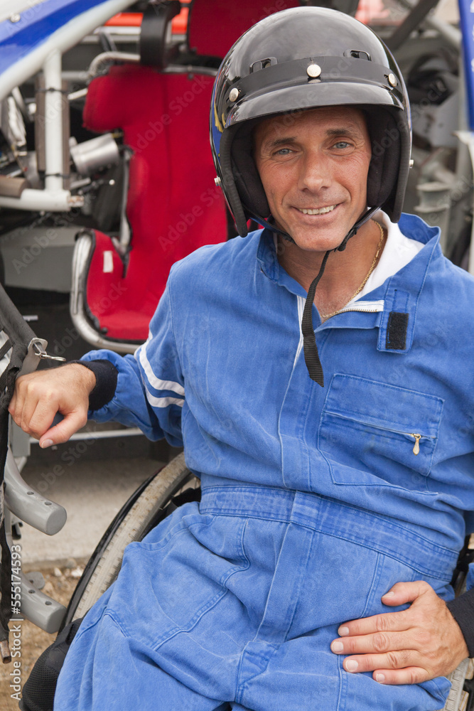 Disabled race car driver with spinal cord injury in wheelchair with his modified race car Disabled race car driver with spinal cord injury in wheelchair with his modified race car