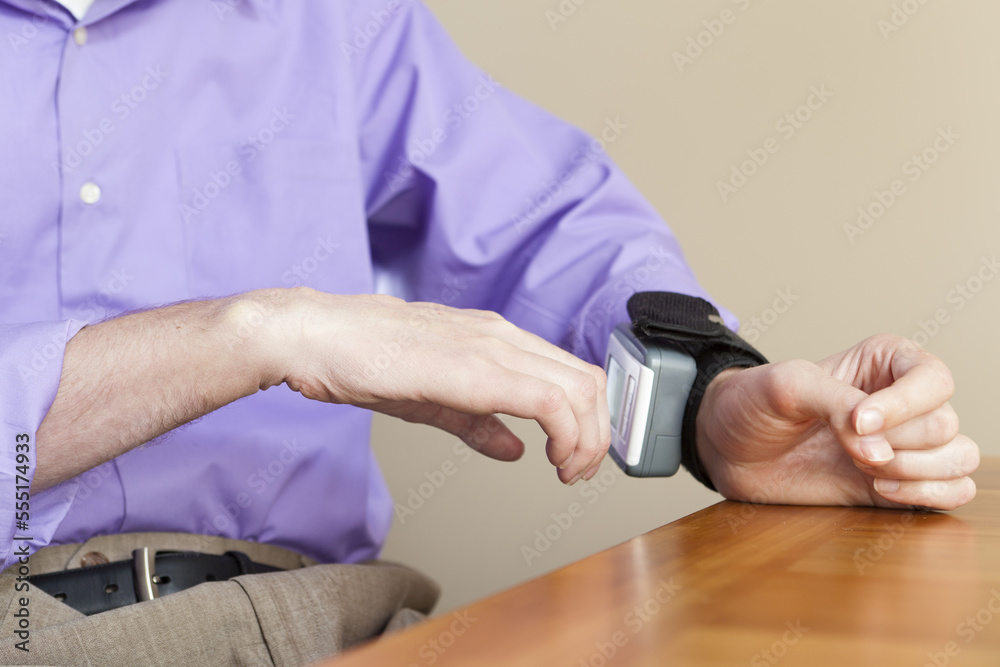 Man with spinal cord injury checking his blood pressure gauge on his wrist Man with spinal cord injury checking his blood pressure gauge on his wrist