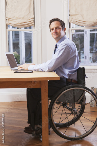 Businessman with spinal cord injury in a wheelchair working on laptop photo