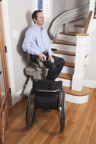 Man with spinal cord injury going up in his motorized stair lift photo