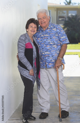 Senior woman standing with her husband with polio holding cane