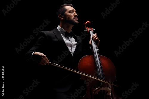 Male artist in a suit and bow-tie playing a cello