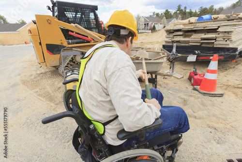 Construction supervisor with Spinal Cord Injury putting shovel into wheelbarrow photo