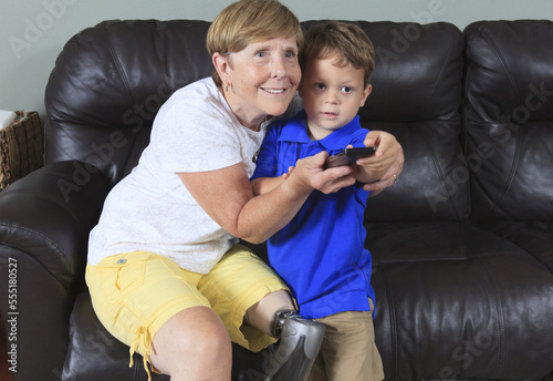 Grandmother with a prosthetic leg with her grandson with a remote control photo