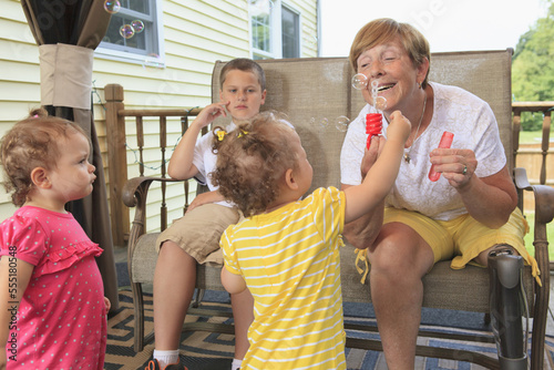 Grandmother with a prosthetic leg blowing bubbles with her grandchildren photo