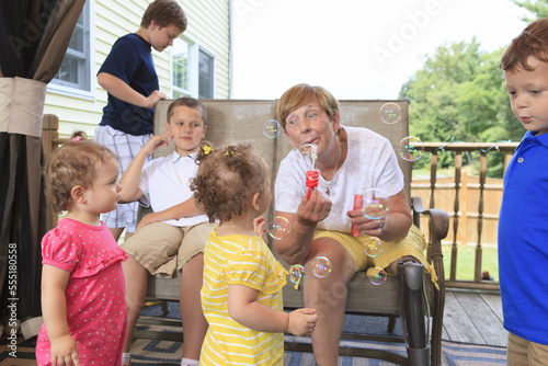 Grandmother with a prosthetic leg blowing bubbles with her grandchildren photo