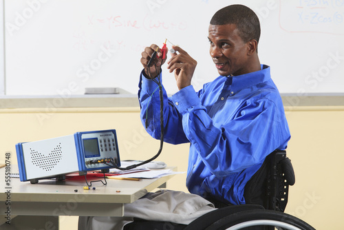 Engineering student in wheelchair from Spinal Meningitis connecting capacitor to LCR impedance meter photo