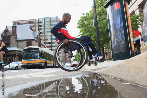 Man in wheelchair who had  Spinal Meningitis going over a curb photo