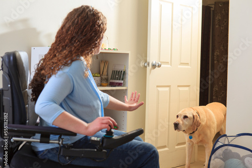 Woman with Muscular Dystrophy in her power chair telling her service dog to stay photo