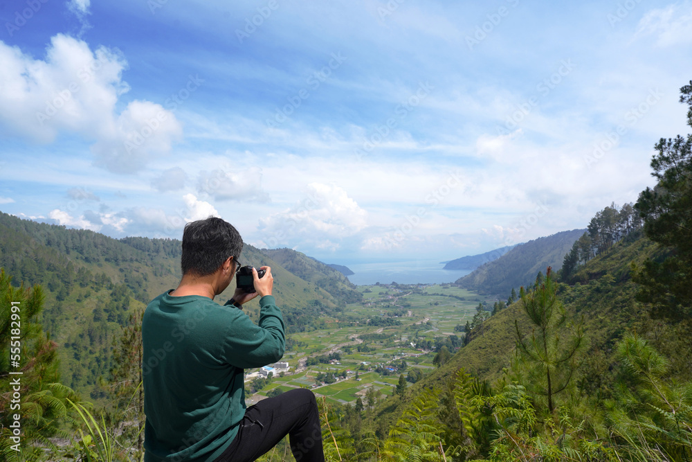Young male photographer shot the beautiful bakkara valley in the background. Male photographer with digital camera.