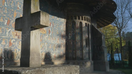 Painted exterior walls and stone cross of Voronet Monastery in Bukovina region photo