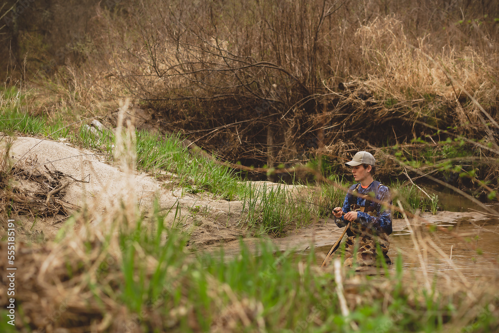 young man kneeling in trout stream young man kneeling in trout stream