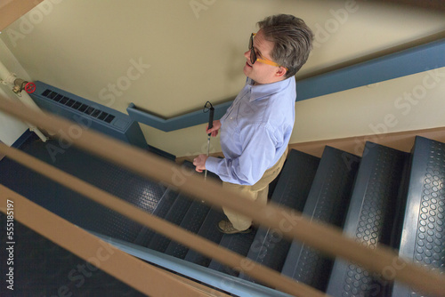 Man with congenital blindness using  his cane to go down a stairwell photo