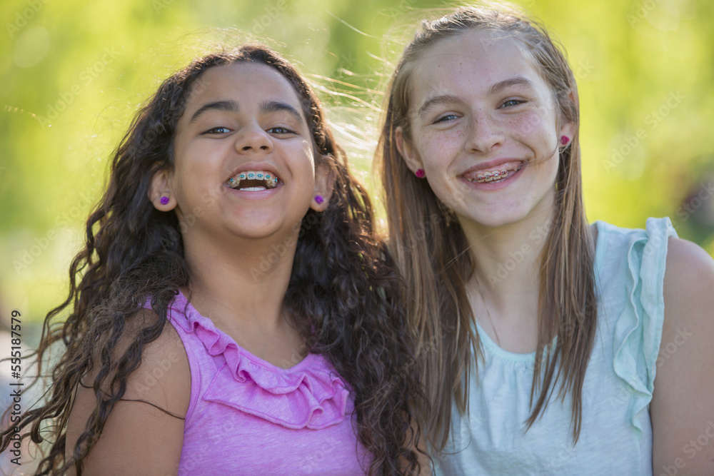 Portrait of two Hispanic teen sisters smiling with braces in a park Portrait of two Hispanic teen sisters smiling with braces in a park