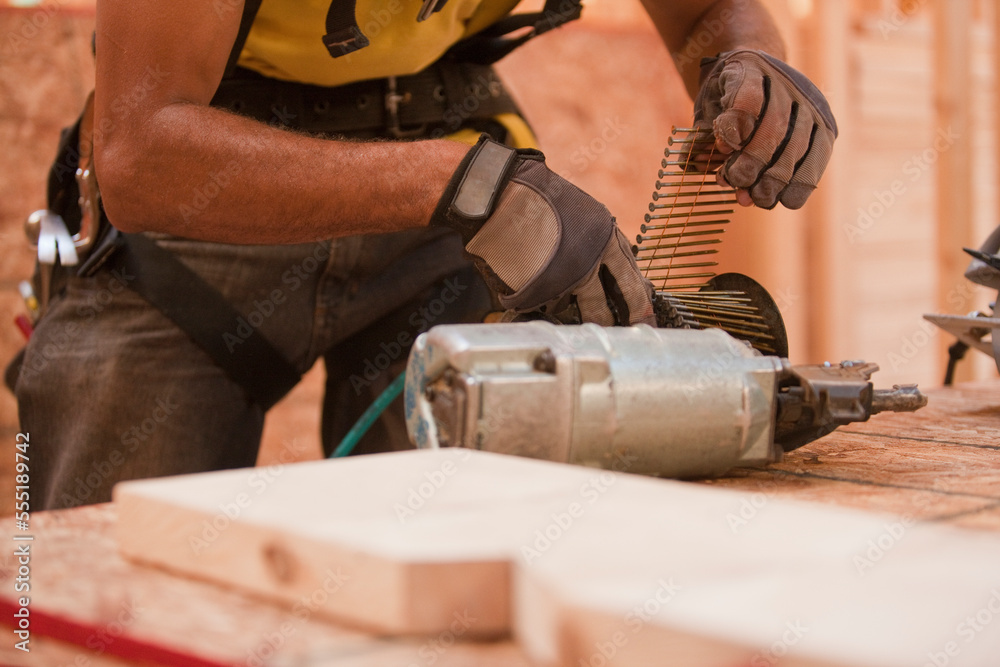 Carpenter reloading circular drum of a nail gun with nails Carpenter reloading circular drum of a nail gun with nails
