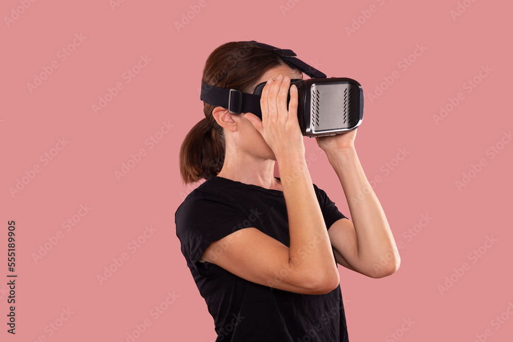 Woman wearing a virtual reality headset, pink background. Woman wearing a virtual reality headset, pink background.